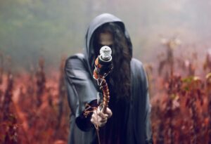 A hooded figure holds a staff in a misty, autumn forest setting, evoking mystery and fantasy.