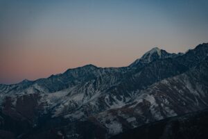 A breathtaking view of the snow-capped mountains in North Ossetia at sunset, showcasing natural beauty and serenity.
