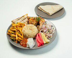 A vibrant Middle Eastern feast featuring chicken, rice, and fresh veggies on a plate.