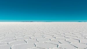 Vast salar with geometric patterns under a clear blue sky in Bolivia's Uyuni.