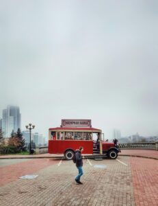 A person walks past a vintage souvenir bus on a foggy day in Minsk, Belarus.