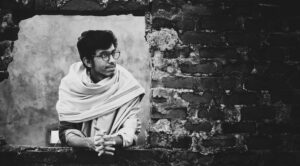 Black and white portrait of a man in Dhaka, highlighting architectural textures.