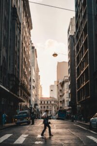 A person crosses a busy street in downtown Sao Paulo amidst urban architecture at sunset.
