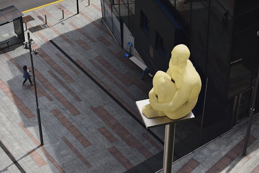 A yellow statue perched high above a modern urban street in Andorra la Vella.